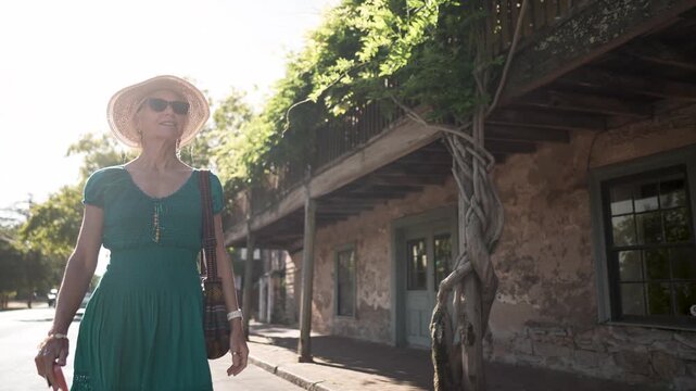 A happy woman walks near the historic Blue Wing Inn museum in Sonoma California, enjoying a sunny day and the beautiful surroundings.