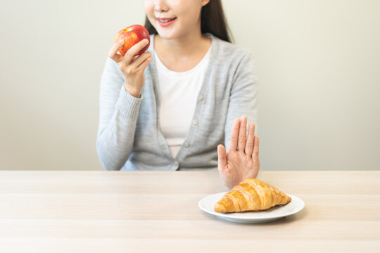 Ketogenic, Low carb, Intermittent Fasting Diet hand push out, refuse butter croissant bread on plate choose apple for good food, fighting to keep it from getting fat. Healthy nutrition of weight loss.