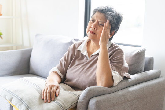 Sick, stress caucasians senior. Mature, adult elderly woman having migraine pain, headache symptom, feeling unhealthy, suffering from dizzy when sitting on sofa. Health care problems of older people.