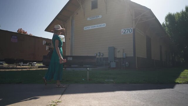 Woman walks around Depot Museum in Sonoma California. She smiles and looks around while enjoying her visit on a sunny day.