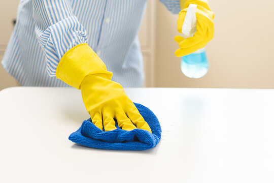 Cleaning professional housekeeping concept. Woman, girl wearing yellow gloves wipe remove bacteria or chores with spray bottle on table at home, use wiping microfiber cloth remove dust in living room.