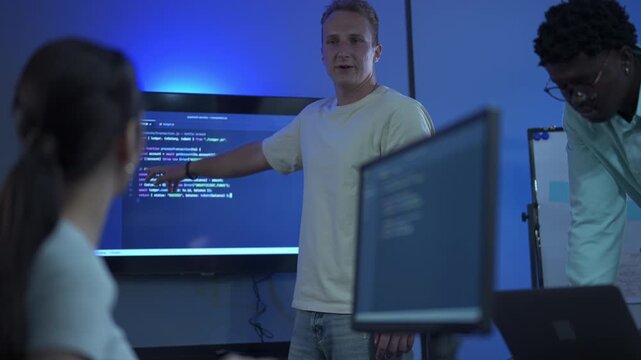 Male programmers leading a meeting and brainstorming together with his colleagues on a coding project in a modern office.