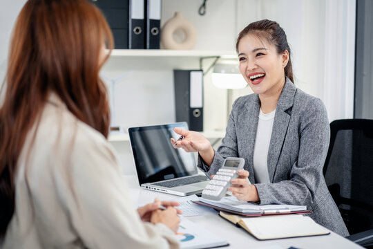 Businesswoman explains financial data with calculator to client colleague in modern office setting for successful planning strategy