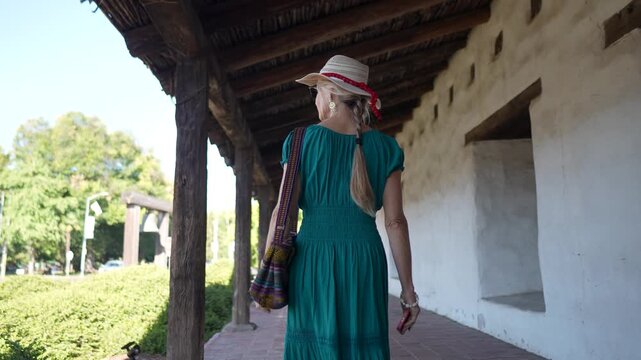A mature woman smiles while walking through the historic Mission church in Sonoma, California, enjoying her visit to the site.