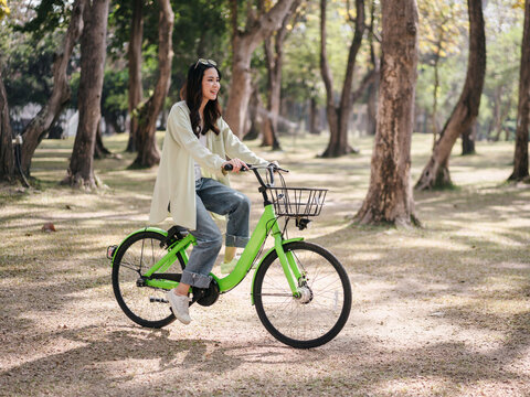 A woman is riding a green bicycle in a park