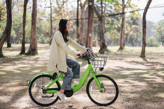 A woman is riding a green bike in a park