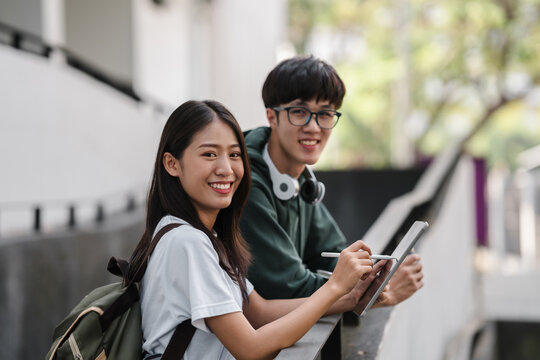 A young man and woman are smiling and holding a tablet