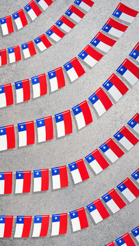 Chilean flags forming bunting garlands on a concrete background, symbolizing national pride