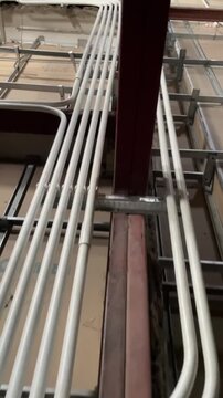 Electrical conduits running along suspended ceiling framework captured in high definition video footage showing complex cable routing installation within a commercial building construction project sit