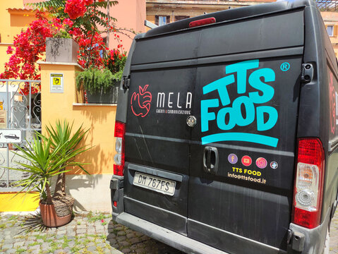 Rome, Italy - May 17, 2026: Delivery van with TTS FOOD branding parked near a colorful building adorned with flowers and greenery in an urban setting