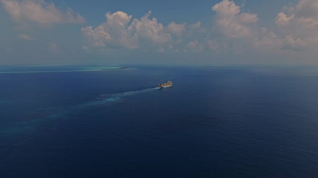 Aerial view of a large ship sailing through the deep blue waters of the Indian Ocean near a remote atoll Dhidhdhoo, Thiladhunmathee Uthur, Maldives.
