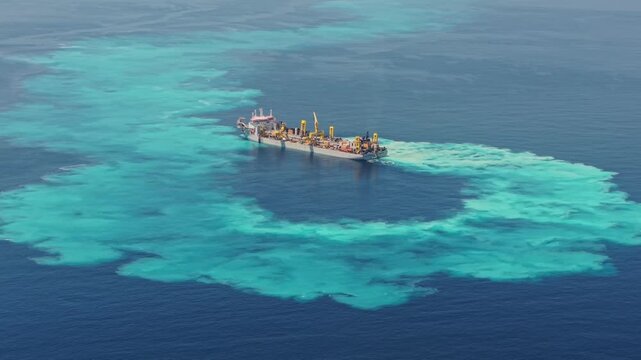 Aerial view of a dredging ship creating a large sediment plume in the turquoise waters of the Indian Ocean near Dhidhdhoo, Thiladhunmathee Uthur, Maldives.