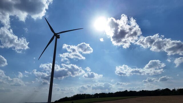 &eacute;olienne en fonction avec le soleil &agrave; l'arri&egrave;re plan en contre-jour, ciel bleu avec des nuages cumulus