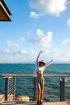 The girl enjoys her vacation. A slender woman stands on the embankment near the sea and enjoys the moment. Summer vacation by the sea.