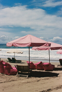 Pink Umbrellas Line Sandy Shore Under a Bright Blue Sky