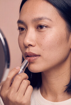Closeup makeup application of a woman applying nude lipstick for natural beauty look and cosmetic makeup tutorial image