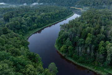 Obraz premium Aerial view of the winding Gauja River at misty sunrise in Gauja National Park, Sigulda, Latvia