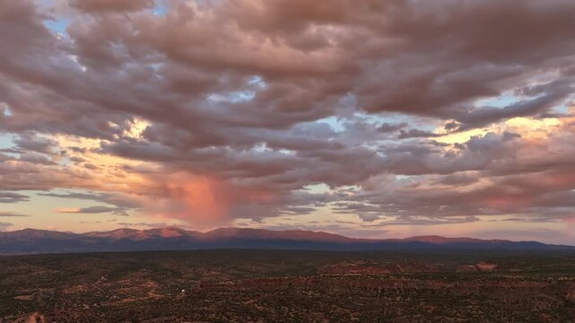 Aerial view of rain showers over the Sangre de Cristo Range at sunset with dramatic clouds and golden light in Los Alamos, NM, United States.
