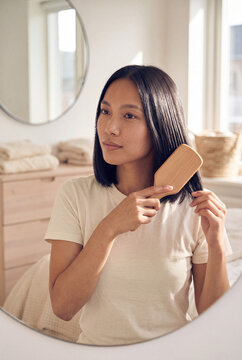 Woman brushing hair in mirror for morning routine lifestyle portrait and grooming banner background