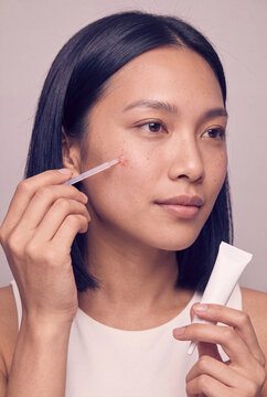 Young woman applying facial serum with dropper for skincare routine and beauty product banner or cosmetic packaging design