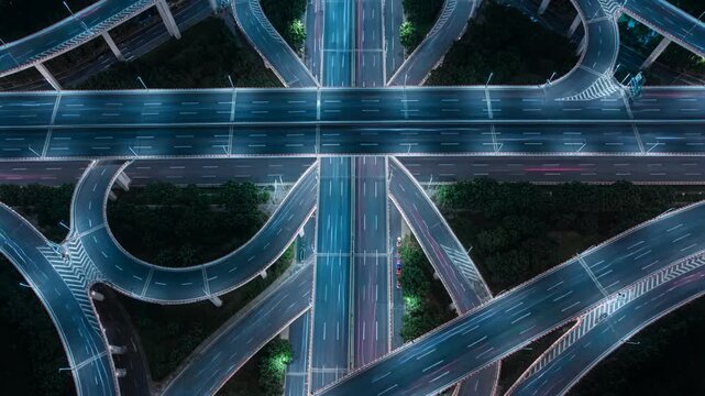 Aerial view of a complex highway junction and city interchange at night featuring glowing road lights and infrastructure connectivity