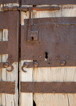 Silent mechanisms guarding a weathered wooden threshold through centuries of quiet endurance