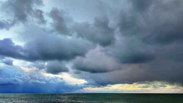 Timelapse of heavy storm clouds rolling over calm sea horizon at dusk in batumi.