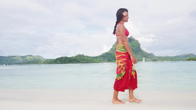 French Polynesia Vacation Travel woman walking on paradise motu beach on holidays on Bora Bora with Mount Otemanu. Girl in pareo in Tahiti, French Polynesia. Raw video of real woman without makeup