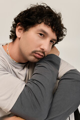Fototapeta premium Young man with stylish moustache poses thoughtfully in a minimalist studio setting