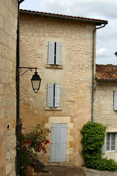 A traditional limestone house with pale blue wooden shutters in the historic village of Aubeterre-sur-Dronne in the Charente region of southwestern France.  