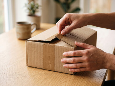 Hands Opening Top Flaps Of Cardboard Shipping Box