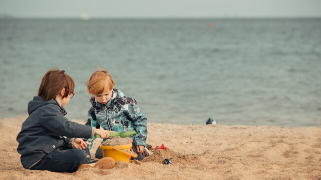 Two Boys Building a Sandcastle Together on a Pale, Overcast Beach