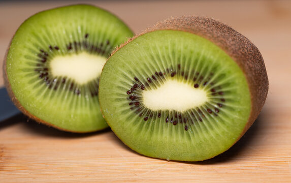 Kiwis on a cutting board, with two halves of a sliced kiwi in the foreground. It contains vitamin C, fiber, and potassium. Nutrition, fruit, healthy lifestyle, fresh, kitchen.