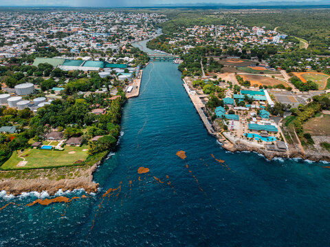 Aerial view of the Chavon River mouth flowing into the Caribbean Sea, with lush vegetation, industrial facilities, and residential areas in La Romana, La Romana Province, Dominican Republic.