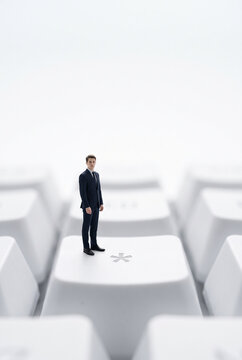 Miniature businessman standing on giant computer keyboard for digital business and IT support concept