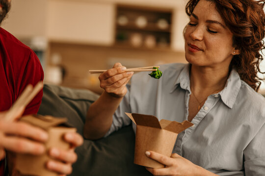 Woman eating healthy takeaway food with chopsticks at home