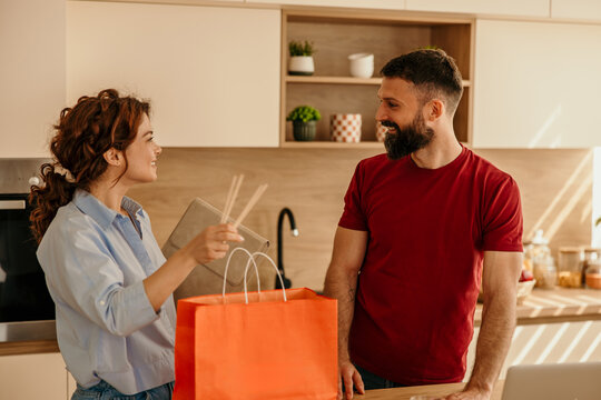 Couple unpacking takeout food delivery in kitchen