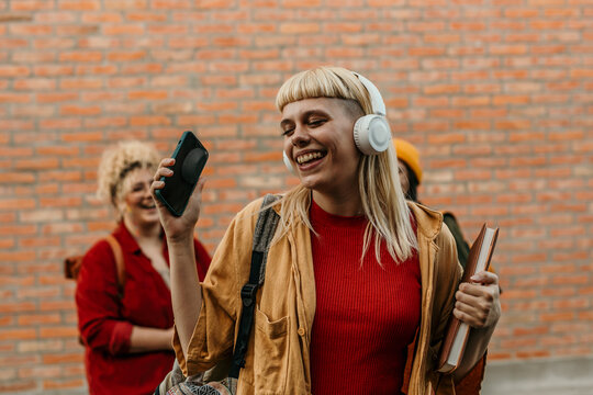 Young student listening to music with headphones on campus