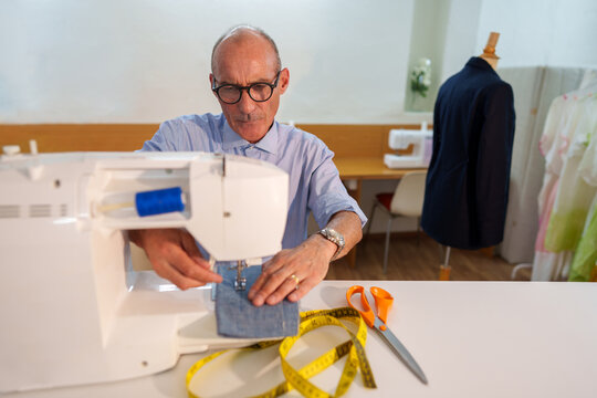 Mature tailor working on a sewing machine, creating a custom garment with precision and craftsmanship