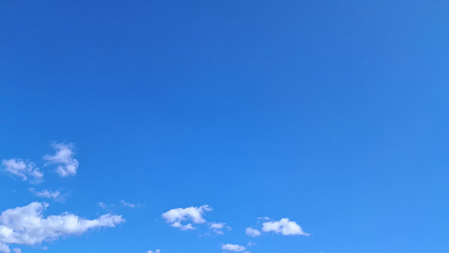 Clear blue sky with fluffy white clouds on a sunny day and large copy space