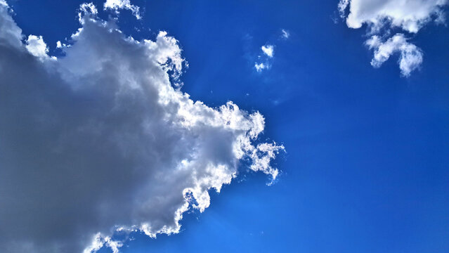 Dramatic white clouds with sun rays in a deep blue sky on a sunny day with copy space