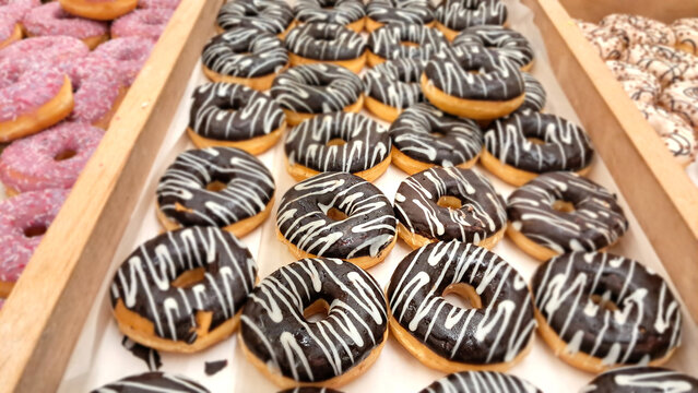 Chocolate glazed donuts with white icing on bakery display
