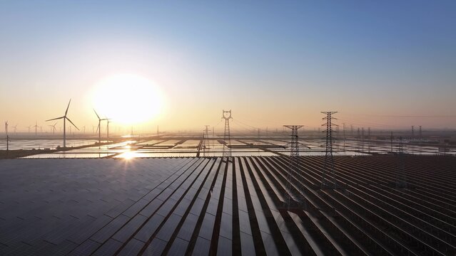 Sunrise view of photovoltaic power station and wind turbines with wetland reflections