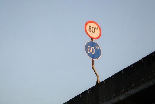 Speed limitation sign boards on a pole at a distressed barrier of highway road. A traffic speed limitation with negative space suitable for transportation themes background or wallpaper. 