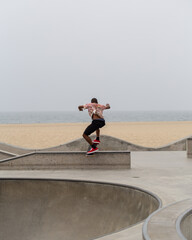 Skateboarder jumping on ledge in outdoor skatepark near the beach © loialstudio