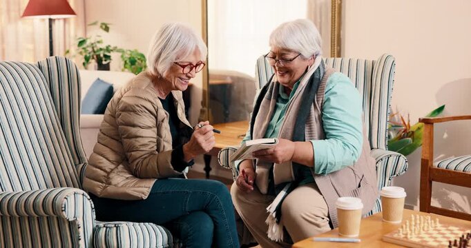 Book, happy and senior friends on sofa in home for bonding, connection and weekend break. Talking, retirement and elderly women in living room with solving sudoku puzzle together in apartment.