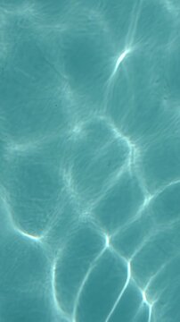 Abstract blue water texture with shimmering sunlight reflections creating a calm pool background. Seamless aquatic surface, perfect as a natural water background and summer design texture.