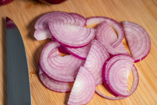 Red onions on a cutting board, sliced with a kitchen knife. Contains vitamin C and fiber., vegetables, vegatarian food, healthy lifestyle, fresh, raw food.