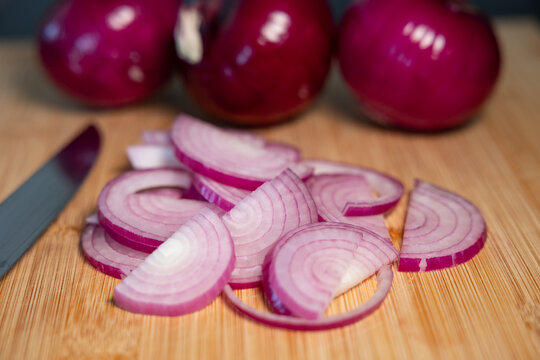 Red onions on a cutting board, sliced with a kitchen knife. Contains vitamin C and fiber., vegetables, vegatarian food, healthy lifestyle, fresh, raw food.