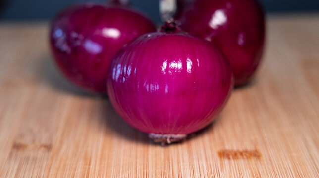 Close-up three red onions on a cutting board. Contains vitamin C and fiber., vegetables, vegatarian food, healthy lifestyle, fresh, raw food.